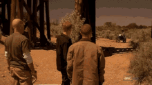 a group of men standing in the desert with a motorcycle in the background that says amc on the bottom