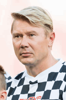 a man wearing a black and white checkered shirt with the word givova on it