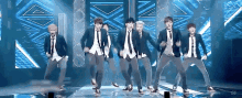 a group of young men in suits and ties are dancing on a stage