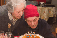 a man wearing a red hat is blowing out candles on a birthday cake