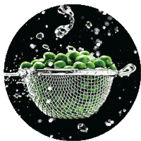 a strainer full of green peas is being filled with water