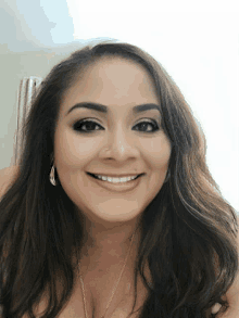 a woman with long hair is smiling and wearing earrings