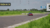a red car is driving on a road with a sign that says 160km / h on it