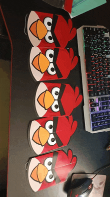 four paper angry birds are lined up on a desk next to a keyboard