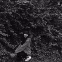 a black and white photo of a woman kneeling in front of a tree with the words " the ker a " above her