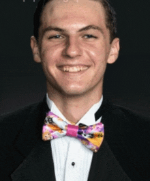 a young man wearing a tuxedo and a colorful bow tie