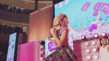 a girl in a colorful dress is dancing in front of a large screen that says sweet