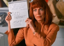 a woman is holding a piece of paper that says " ded report asap " .