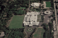 an aerial view of a large white building surrounded by greenery