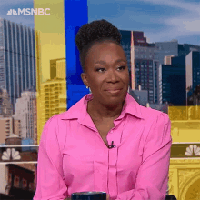 a woman in a pink shirt is sitting in front of a city skyline with a cup of coffee .