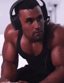 a man wearing headphones and a black tank top looks at something