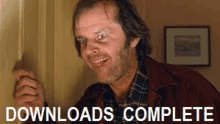 a man in a plaid shirt is standing in a doorway with the words `` downloads complete '' above him .