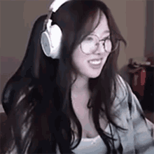 a woman wearing glasses and headphones is sitting in a chair .