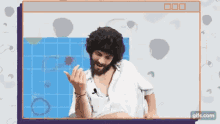 a man with a beard is giving the middle finger while sitting in front of a screen .