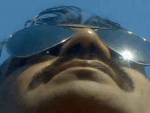 a close up of a man 's face wearing sunglasses .