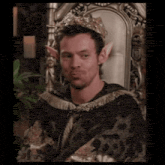 a man wearing a crown and elf ears is sitting on a chair .