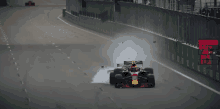 a red bull race car is driving down a track with a red sign behind it that says ' live broadcast '