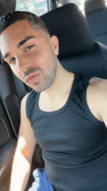 a man in a black tank top is taking a selfie in a car