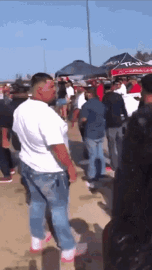 a man in a white shirt stands in front of a crowd of people in front of a tent that says tulsa on it