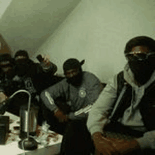 a group of masked men are sitting around a table .