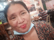 a woman wearing a face mask is sitting at a table in a restaurant