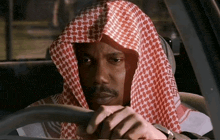 a man wearing a keffiyeh driving a car