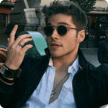 a man wearing sunglasses and a ring is sitting in front of a store that says wine