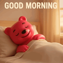 a red teddy bear is laying in a bed with the words good morning written above it