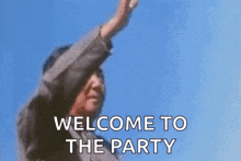 a man is standing in front of a blue sky with his arms in the air and saying `` welcome to the party '' .