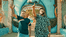 two men are standing in front of a large blue statue