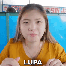 a woman in a yellow shirt is giving a thumbs up and the word lupa is on her face