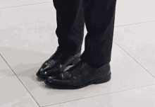 a pair of black shoes are on a tile floor