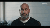 a bald man with a beard is wearing a black shirt with netflix written on the bottom