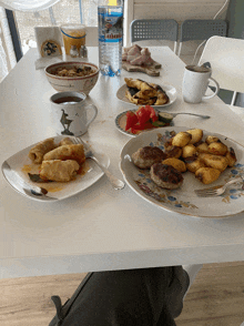 a table with plates of food and a bottle of rubini water