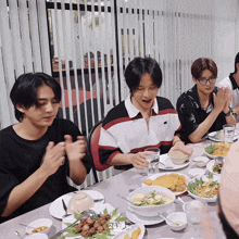 a group of young men are sitting at a table with plates of food and the number 24 on the bottom right