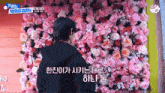 a man stands in front of a wall of pink flowers with tws debut show written on the bottom