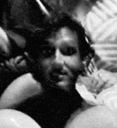 a black and white photo of a man laying on a bed with headphones on .