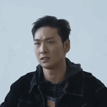 a man wearing a black jacket and a striped shirt is looking at the camera .