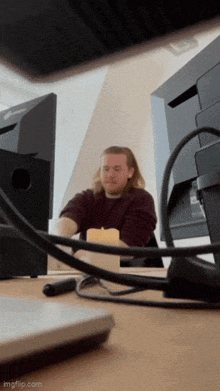 a man is sitting at a desk with a candle in front of a computer monitor .