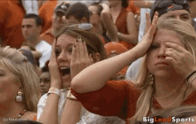 a woman covering her face with her hands in a crowd of people with big lead sports written on the bottom of the image