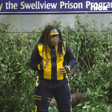 a man in a yellow and black outfit stands in front of a sign that says the swellview prison program