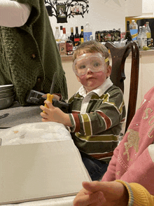 a little boy wearing goggles holds a yellow object