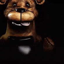 a close up of a teddy bear 's face with a tongue sticking out in a dark room .