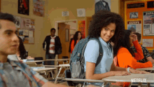 a girl with a backpack sits at a desk in a classroom with a sign that says egypt on it