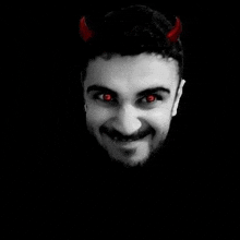 a man with red eyes and horns on his head is smiling .