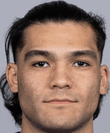 a close up of a young man 's face with long hair and a ponytail .