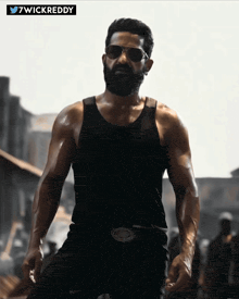 a man with a beard is wearing sunglasses and a black tank top with the hashtag 7wickreddy