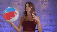 a woman in a red crop top is holding a colorful object in her hands