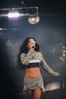 a woman singing into a microphone wearing sunglasses