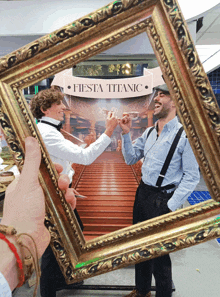 two men are toasting in front of a fiesta titanic poster